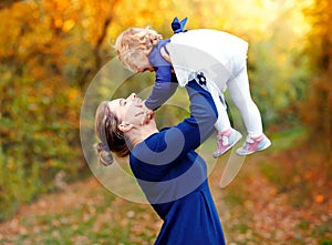 Happy young mother having fun cute toddler daughter, family portrait together. Woman with beautiful baby girl in nature