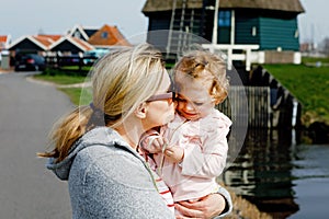 Happy young mother having fun cute toddler daughter, family portrait together. Woman with beautiful baby girl walking in