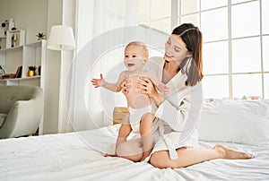 Happy young mother is having fun playing with her newborn baby son