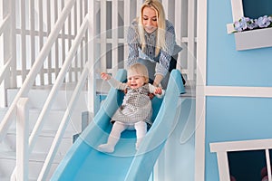 Happy young mother with her baby boy playing in colorful playground for kids