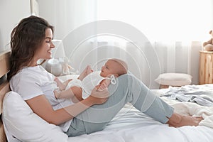 Happy young mother with her baby on bed at home