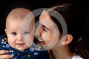 Happy young mother with her daughter on her hands on a black bac