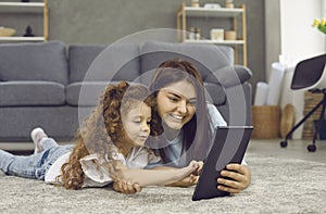 Happy young mother and her little daughter playing games on a digital tablet together