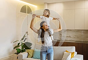 Happy young mother and her preschool daughter playing together at home