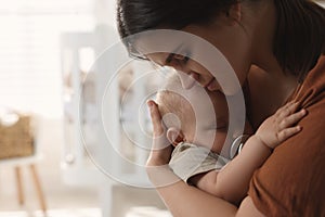 Happy young mother with her sleeping baby at home. Space for text