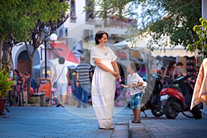 Happy young mother and her son walking in city