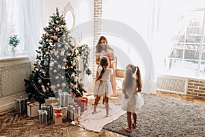 Happy young mother and her two charming daughter in nice dresses