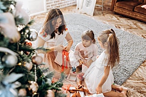 Happy young mother and her two charming daughters in nice dresse