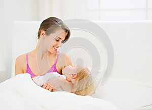 Happy young mother holding sleeping baby