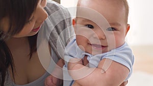 Happy young mother kissing little baby at home