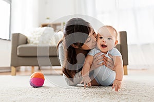 Happy young mother kissing little baby at home