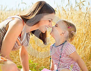 Happy young mother with little daughter on field in summer day