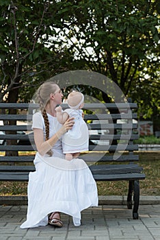 Happy young mother with lovely baby girl on Park bench. Vertical frame