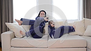 Happy young mother lying on bed and watching tv