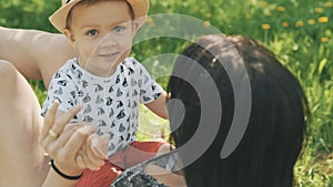 Happy young mother playing on blanket with her cute son under tree at park