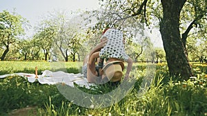 Happy young mother playing on blanket with her little son under tree at park