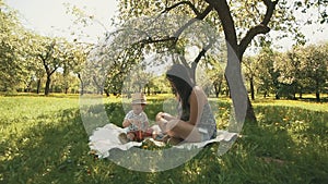 Happy young mother playing on blanket with her son under tree at park