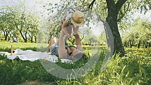 Happy young mother playing on blanket with her son under tree at park