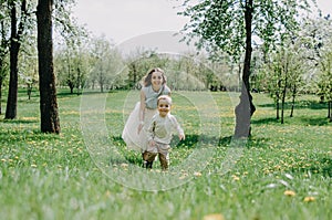 Happy young mother playing and having fun with her little baby son on sunshine warm spring or summer day