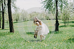 Happy young mother playing and having fun with her little baby son on sunshine warm spring or summer day