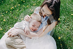 Happy young mother playing and having fun with her little baby son on sunshine warm spring or summer day
