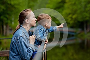 Happy young mother playing and having fun with her little baby son on warm spring or summer day in the park. Happy family concept