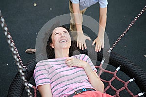 Happy Young mother playing with her son on the playground, hugging, laughing