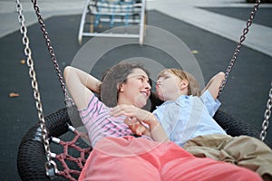 Happy Young mother playing with her son on the playground, hugging, laughing