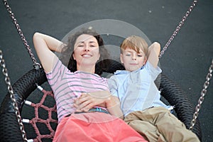 Happy Young mother playing with her son on the playground, hugging, laughing