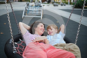 Happy Young mother playing with her son on the playground, hugging, laughing
