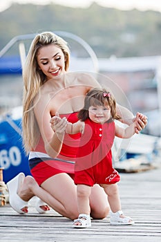 Happy young mother with a young daughter near Yacht Club