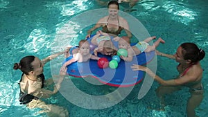 Happy young mothers playing with her babys in pool