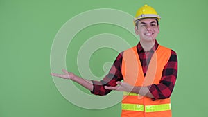 Happy young multi ethnic man construction worker showing something