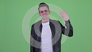 Happy young multi ethnic man with leather jacket waving hand
