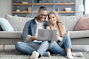 Happy Young Multicultural Couple Relaxing With Laptop On Floor At Home