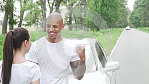 Happy young multiethnic couple laughing resting from driving during road trip