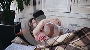 Happy young multiethnic couple lying under blanket, hugging and kissing. Tenderly morning of man and woman on the bed.