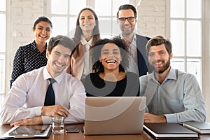 Happy young multiethnic team posing at workplace table