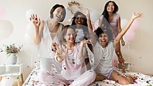 Happy young multiracial girlfriends in nightwear posing for funny photo.