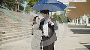 Happy young muslim couple hiding from sun under umbrella.