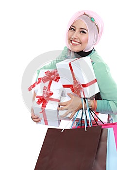 Happy young muslim woman with shopping bag and gift boxes