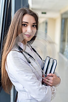 happy young nurse in uniform with stethoscope smiling in corridor.