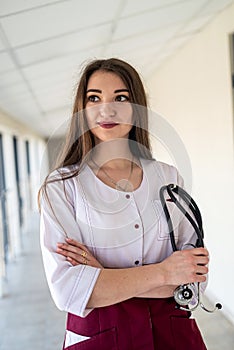 happy young nurse in uniform with stethoscope smiling in corridor.