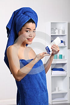 Happy young oriental woman using moisturiser photo