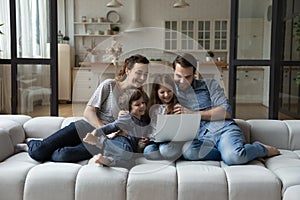 Happy young parents and adorable little children using computer.