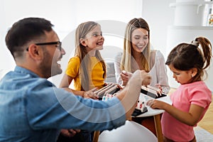 Happy young parents and children having fun, playing board game at home