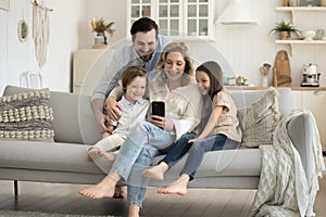 Smiling parents with children using cellphone at home