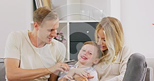 Happy young parents and cute kid son play patty cake in bedroom, playful family mother and father with little child boy