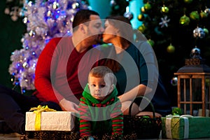 Happy young parents kiss and their little son crawls near Christ