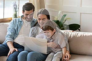 Happy young parents with little son using laptop together